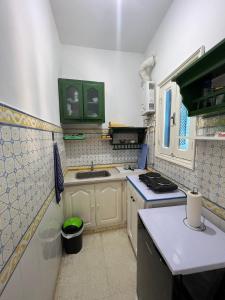 a small kitchen with a sink and a stove at Maison Ghemrini in Sidi Bou Saïd