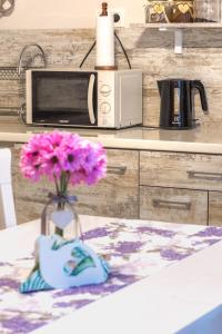 um vaso com flores cor-de-rosa no balcão da cozinha em Rosa em Karpacz