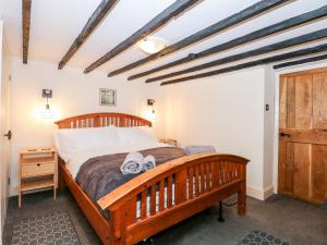 1 dormitorio con cama de madera y toallas en Butterfly Cottage en Alford