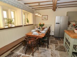 Il comprend une cuisine équipée d'une table en bois et d'un réfrigérateur. dans l'établissement The Farmhouse, à Keighley