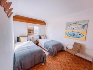 a bedroom with two beds and a chair at Just Like Home - AP da Costa in Caminha