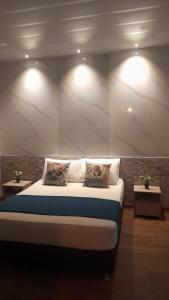 a bedroom with a bed with two pillows and two tables at Hostal The Garden Lleras 10 in Medellín