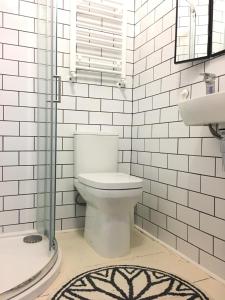 a white bathroom with a toilet and a shower at Augusta garden apartment in Sheringham +30 photos