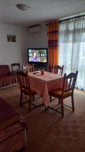 a living room with a table with chairs and a tv at Maja Apartman in Igalo