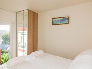 a white bedroom with a bed and a window at The Bolthole at Bay View House in Salcombe