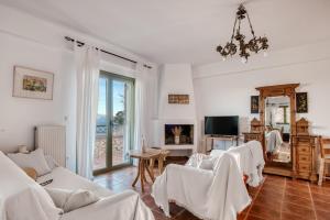 a living room with white furniture and a tv at Diodati Villas in Nikiana