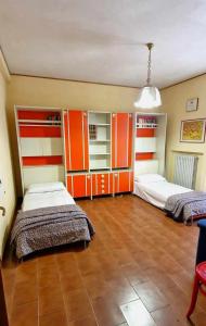 2 Betten in einem Zimmer mit orangefarbenen und weißen Schränken in der Unterkunft La Corte sul Conero Casa Vacanze in Camerano