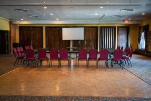 une salle de conférence avec des chaises rouges et un écran de projection dans l'établissement Sheridan Inn - Best Western Signature Collection, à Sheridan