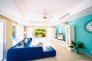 a blue living room with a blue couch and a tv at Luxury Villa Iberosta - 4BDR, Private Beach, Pool & Jacuzzi in Punta Cana