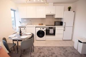 a kitchen with a table and a white refrigerator at Walnut Flats-F5, Stylish 1-Bedroom - Parking, Netflix, WIFI - Close to Oxford, Bicester & Blenheim Palace in Kidlington