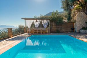 a blue swimming pool with a table and chairs at Diodati Villas in Nikiana