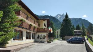 ein Auto, das auf einem Parkplatz neben einem Gebäude parkt in der Unterkunft IHR Hotel Villa Emma in Canazei