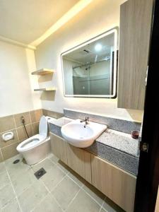 ein Badezimmer mit einem Waschbecken, einem WC und einem Spiegel in der Unterkunft Al Caja Resort Condotel in Manila