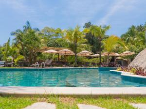 a swimming pool with chairs and umbrellas at Velas do Engenho in Ilhabela