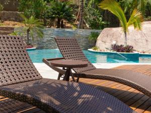 two wicker chairs and a table next to a pool at Velas do Engenho in Ilhabela