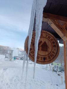 una señal de madera con nieve colgando de ella en Little Trees Apartment, en Benecko