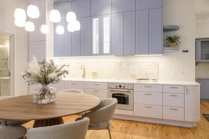 a kitchen with white cabinets and a wooden table with chairs at Lossi Old Town apartment with sauna in Tartu +10 photos