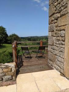 2 chaises assises sur une terrasse en bois avec un mur en pierre dans l'établissement Small Gte For 2 With Pool In Peaceful Burgundy, à Sailly