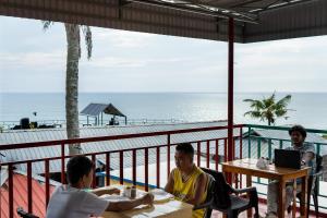 Avanthi Homestay في فاركَالا: مجموعة من الرجال يجلسون على طاولة على الشاطئ