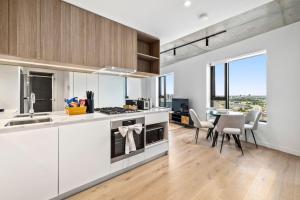 een keuken met witte kasten en een tafel met stoelen bij Stunning Stature Southbank 2bed in Melbourne