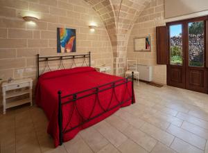 トッリチェッラにあるMasseria Giustinianiのレンガの壁に赤いベッドが備わるベッドルーム1室