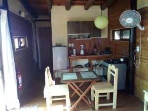 Sietevestidos Casa Ecológica - Punta Negra في Punta Colorada: مطبخ مع طاولة وكراسي وثلاجة