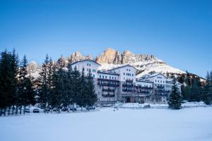 a building in front of a snow covered mountain at Grand Hotel Carezza Multiproprietà in Carezza al Lago