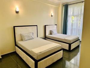 two beds in a room with a window at Oceans-Opulence/3BR-5 BEDS in Dar es Salaam