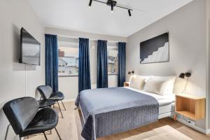 - une chambre avec un lit, deux chaises et une télévision dans l'établissement Bispegata 5 - Studio Apartment hotel, à Tromsø