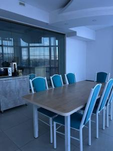 una sala de conferencias con una mesa de madera y sillas azules en Sayak hostel, en Karakol