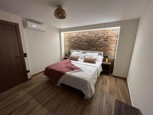 - une chambre avec un lit et un mur en briques dans l'établissement Apartamento Peña Cortada, à Alhama de Aragón