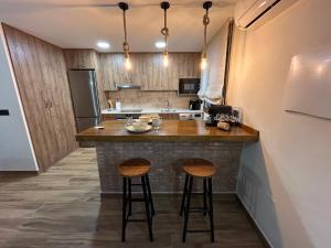 a kitchen with two bar stools at a counter at Apartamento Peña Cortada in Alhama de Aragón +23 photos