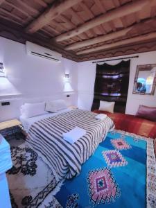 a bedroom with a bed and a rug on the floor at Auberge La Fibule Du Dades in Aït Idaïr