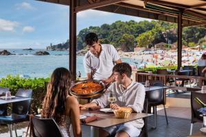 a man serving a pizza at a restaurant at Albamar Apartaments in Lloret de Mar