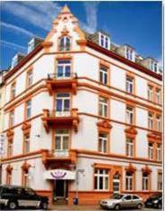 un gran edificio blanco con coches estacionados frente a él en Hotel Columbus, en Frankfurt