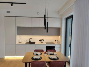 a kitchen with a wooden table and chairs and a kitchen with white cabinets at New Nordic 2BR: Beach & Forest, Family-Friendly in Tallinn