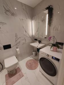 a white bathroom with a toilet and a sink at New Nordic 2BR: Beach & Forest, Family-Friendly in Tallinn