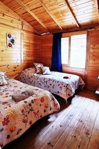 a bedroom with two beds in a wooden cabin at Cabaña Caracolí. Tranquilidad vía a la laguna in Ubaque