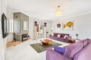 een woonkamer met paarse banken en een open haard bij Villa Cambria by OCvillas in Albufeira