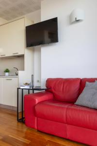 un sofá rojo en la sala de estar con TV de pantalla plana en Lo Spettacolo, en Macerata