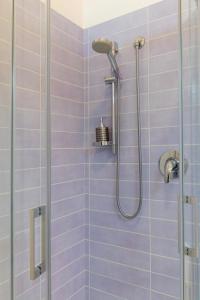 y baño con ducha de azulejos morados. en Lo Spettacolo, en Macerata