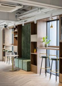 Zimmer mit Tischen, Stühlen und einer grünen Bank in der Unterkunft Magnificent Apartments at Ten Degrees in Croydon in Croydon