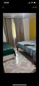 a bedroom with two beds and a window with curtains at Aconchego da Lu in Angra dos Reis