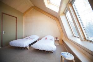 two beds in a room with a window at Bed & Coffee Skilleplaatsje in Den Burg