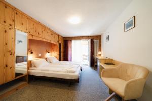 um quarto com uma cama e uma cadeira num quarto em Hotel Old JNN em Klosters Serneus