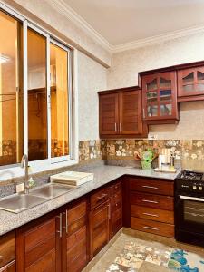 a kitchen with wooden cabinets and a sink at Oceans-Opulence/3BR-5 BEDS in Dar es Salaam
