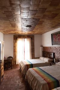 a bedroom with two beds and a wooden ceiling at Hotel Casa Mixteca in Huajuapan de León