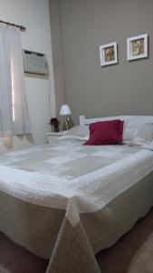 Una cama blanca grande con una almohada roja. en Azahares del Ayuí en Concordia