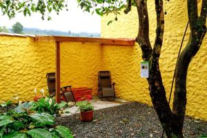 a yellow building with two chairs and a tree at Hostal Café Racer in Jardin