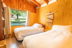 two beds in a room with a window at Cabañas Rápidos del Río Baker in Puerto Bertrand